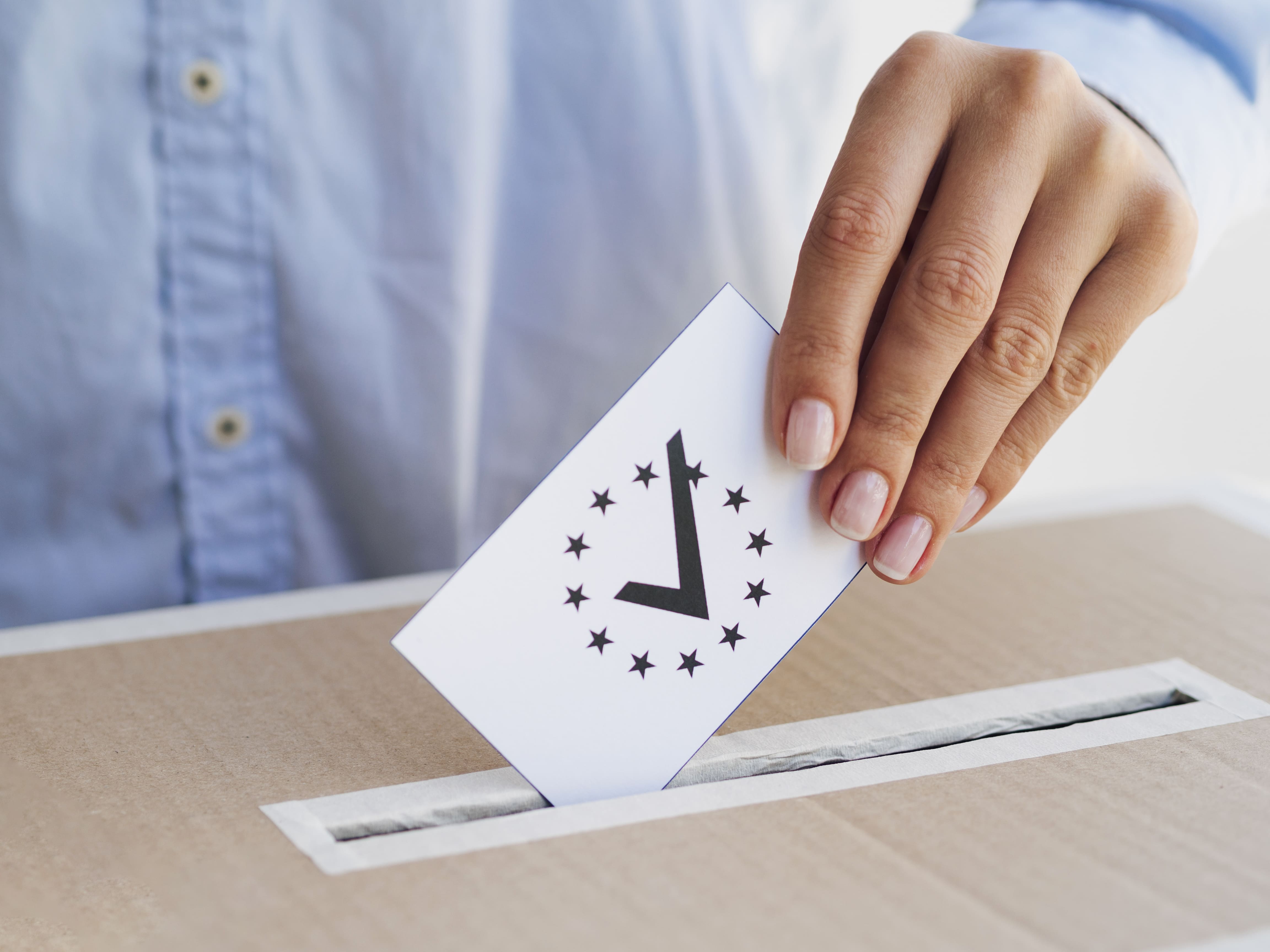 uma mão inserindo um voto na urna -direito eleitoral
